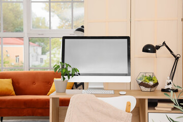 Comfortable workplace with modern computer and folding screen in living room