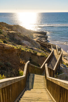 Stairs on a boardwalk leading around a cliff face in the sunshine