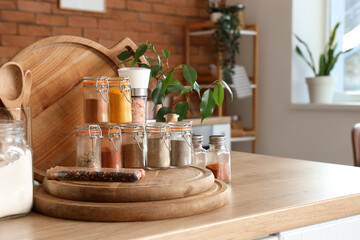 Jars with different spices and chopping boards on table in kitchen