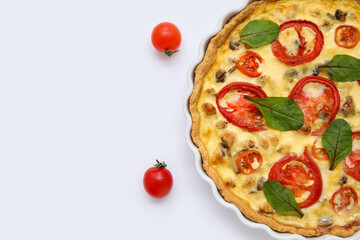 Delicious tomato tart with spinach leaves on white background