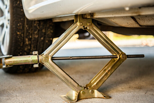 Jacking up car to change flat tyre with small hand jack