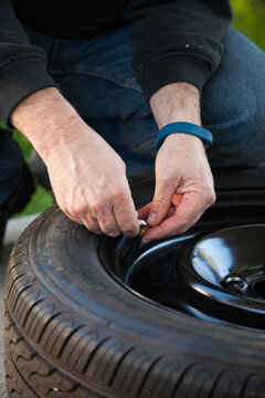 Man releasing air pressure from spare car tyre