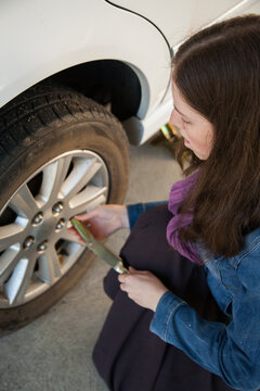 Teen girl learning how to change flat tyre unscrewing wheel nuts