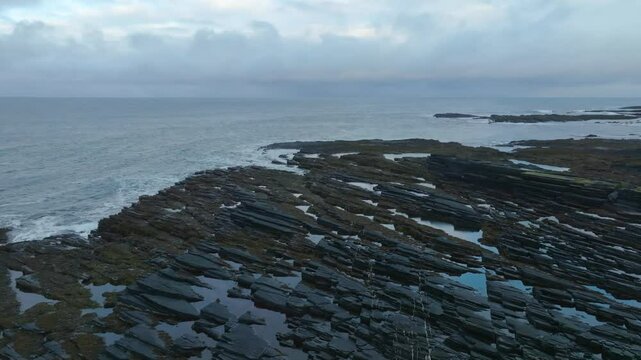 Drone footage capturing the distinctive flysch formation with sedimentary rock layers stacked along the coastal cliffs of Cape Nemetsky, Vaida Bay