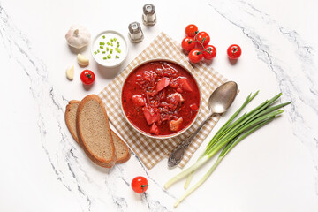 Bowl of tasty Ukrainian borscht with sour cream, green onion and bread slices on white background