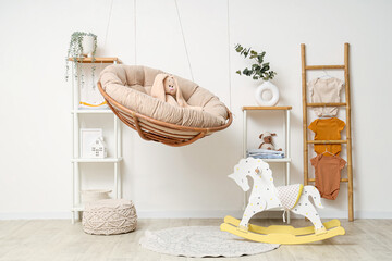 Interior of children's room with hanging armchair, ladder and baby bodysuits