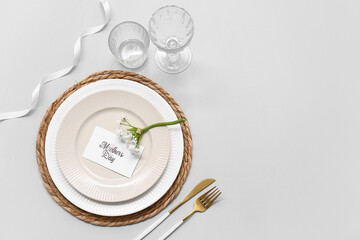 Stylish table setting with greeting card and beautiful flowers on grey background. Mother's Day celebration