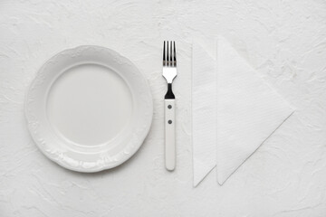 Plate with fork and paper napkins on white grunge background