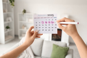 Female hands marking period in menstrual calendar at home, closeup