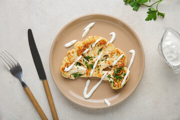 Plate of grilled cauliflower steak with sauce and parsley on white background