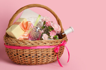 Fototapeta na wymiar Gift basket with spring flowers and perfume on pink background