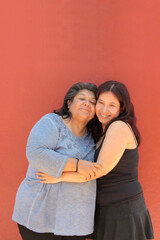 A 50-year-old Latina mother and her 18-year-old daughter hug and kiss each other to show their love and celebrate Mother's Day