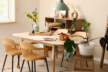 Interior of room with dining table, wooden shelf unit and palm plant