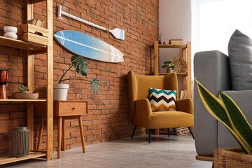 Interior of stylish living room with grey sofa, shelving units and surfboard