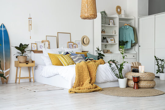Fototapeta Interior of light bedroom with surfboard, closet and plants