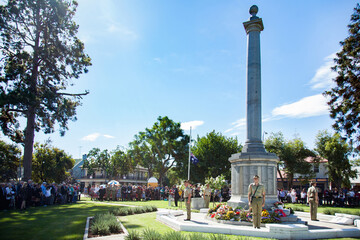 Australian soldiers standing around a cenotaph at an ANZAC Day service