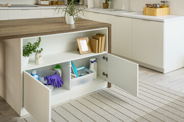Table with cleaning supplies and storage basket in modern kitchen