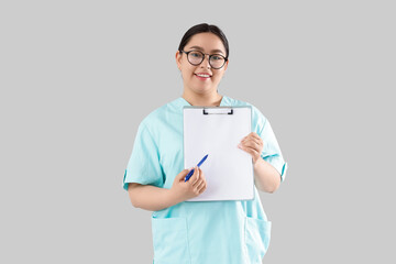 Female doctor with blank clipboard on light background