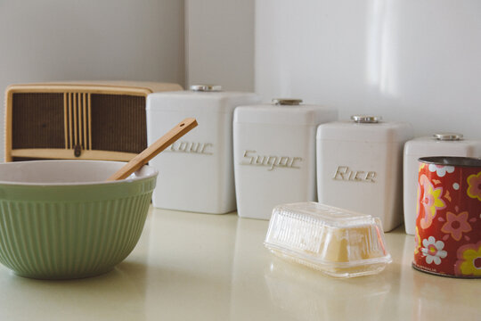 A retro style kitchen scene with radio, mixing bowl, canisters, butter dish and sifter