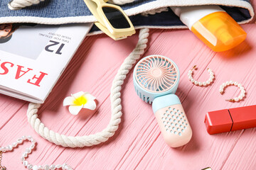 Female summer accessories and mini fan on pink wooden background