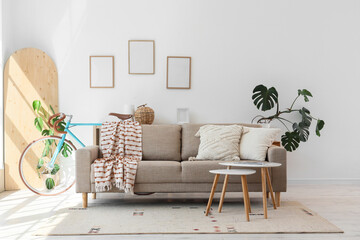 Interior of living room with bicycle, sofa and blank frames
