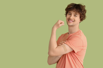 Young man with applied medical patch showing muscles on green background. Vaccination concept