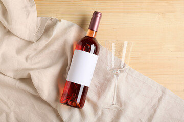 Bottle of wine with blank label and glass on wooden background