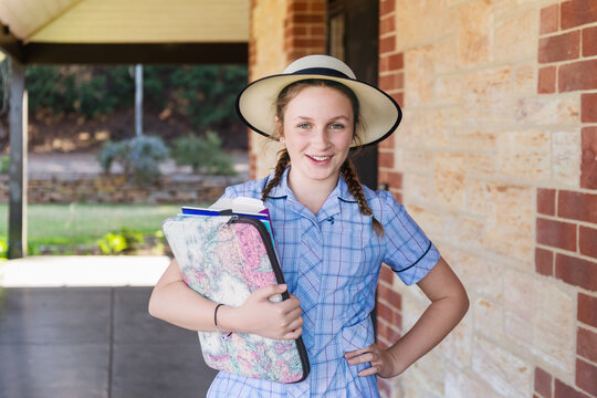 Teen girl in school uniform with books and laptop
