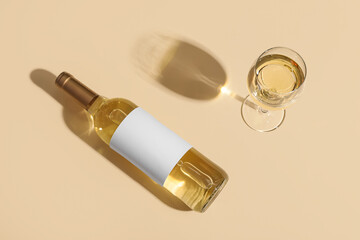 Glass of wine and bottle with blank label on beige background