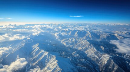 Aerial View of Snow Covered Mountain Range Under a Clear Blue Sky