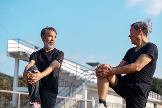 Active senior men stretching together outdoors, promoting wellness and fitness in later life.