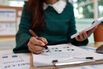 A professional woman wearing a headset works at her desk in a modern office, communicating with a client via computer.