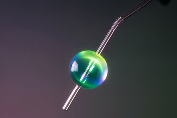 Glass Straw With Sphere Ornament Against Dark Background