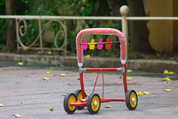 Picture of a baby walker. Wheel, steel, metal, red, yellow, rubber, pavement, fulcrum, learning,...