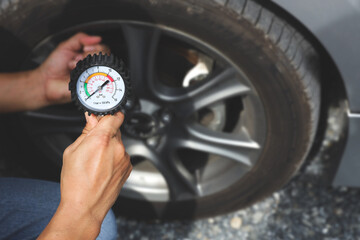 Auto mechanic holding car tire pressure check equipment tool to checking low tire pressure inflating tires to or refill or air inflate to safety and car care service maintenance inspection. © Eakrin