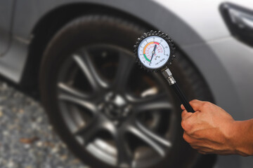 Auto mechanic holding car tire pressure check equipment tool to checking low tire pressure inflating tires to or refill or air inflate to safety and car care service maintenance inspection. © Eakrin