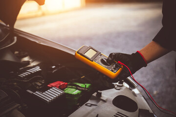 Car mechanic technician use measuring tool to check electrical voltage battery low energy problem for car care service maintenance and re charger or jump start or change new battery replacement.