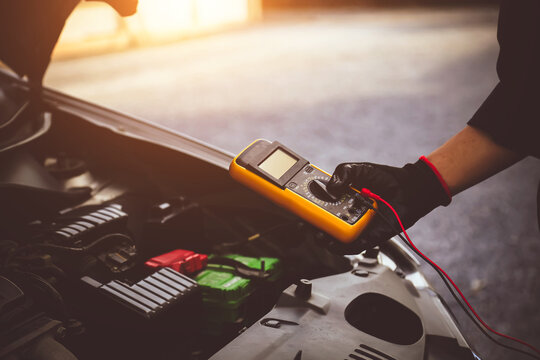 Car mechanic technician use measuring tool to check electrical voltage battery low energy problem for car care service maintenance and re charger or jump start or change new battery replacement.