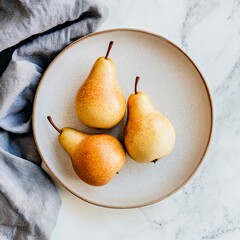Three ripe pears on a ceramic plate with a textured gray cloth.