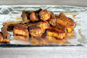 Grilled pork ribs served in foil. The ribs are golden brown, crispy on the outside and juicy on the inside, with a delicious texture. Close-up
