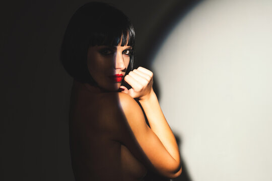 Sensual portrait of a young nude sexy woman. Sexy model posing in studio shadow lighting. Fashion shoot of beauty woman. Sexy model with fashion makeup. Sexy brunette woman.