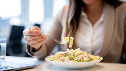 Woman enjoying a fresh pasta salad at her office desk.