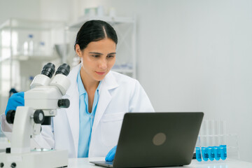 scientist and researcher laboratory is working attentively laptop, with microscope and test tubes...