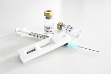 Vial of Covid-19 vaccine, 1 ml plastic syringe with needle and Positive test result of Covid-19 antigen test kit isolated on the white background