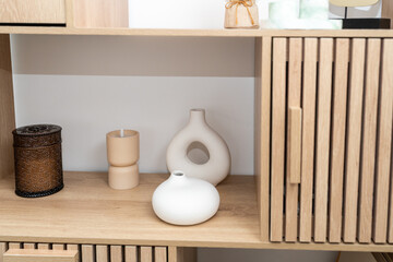 A stylish arrangement features ceramic vases and decorative candle holders. The warm wooden shelf highlights the minimalist design, enhancing the cozy atmosphere of the room.
