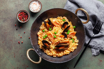 Traditional spanish seafood paella with rice, mussels, shrimps in a pan on concrete background. Top view. Flat lay