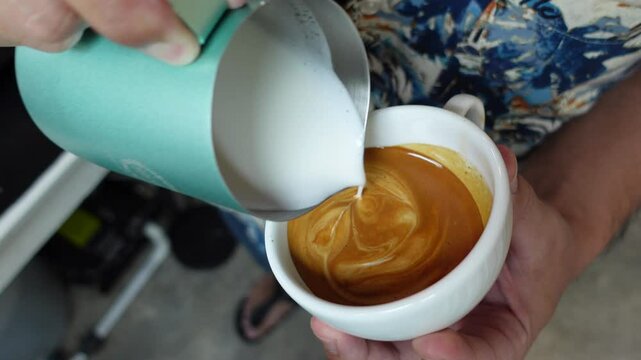 Barista Pouring Latte Art &ndash; Creating Rosetta Pattern in Cappuccino Cup, forming a beautiful latte art design. Ideal for coffee ads, tutorials, and aesthetic visuals.