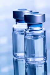 Vial with clear liquid and metal cap on reflective surface in medical setting