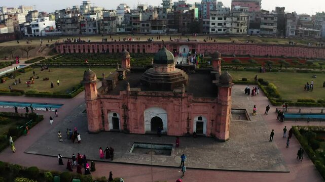 Aerial: Drone Panning Shot Of Men And Women Exploring Famous Fort In Residential City Against Clear Sky - Dhaka, Bangladesh
