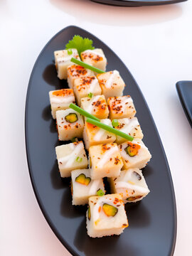 Delicious sushi cubes arranged appealingly on a black plate, enhanced by the green onion and sesame seeds, showcasing freshness and gourmet culinary design.